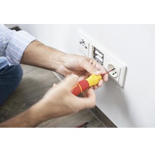 Elektricien installeert stopcontact met schroevendraaier
