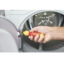 Een man gebruikt een schroevendraaier om een schroef aan een wasmachinedeur vast te draaien.