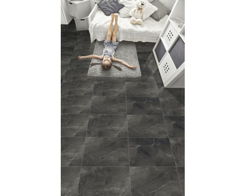 Meisje ligt op tegelvloer in kinderkamer.