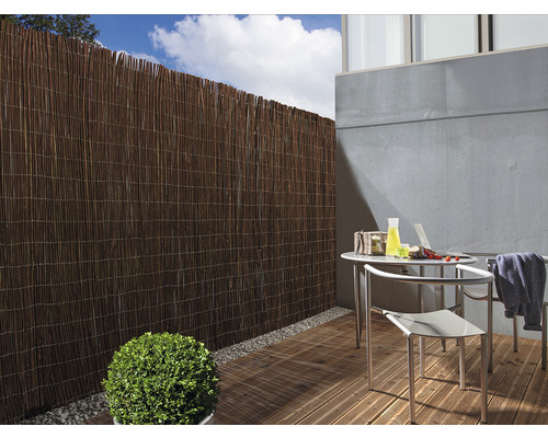 Scene met een terras voorzien van een privacyscherm en tuinmeubelen.