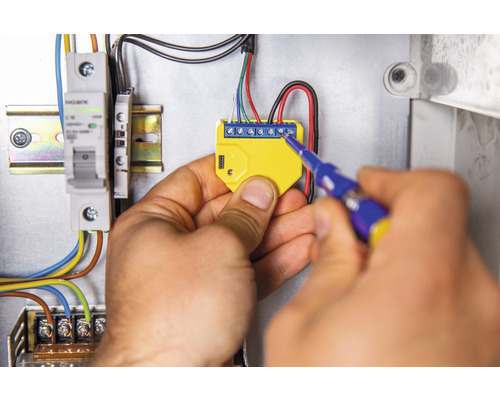 Elektricien monteert elektronisch onderdeel met schroevendraaier in verdeelkast