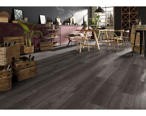 Interieur van een kamer met donkergrijze laminaatvloer, houten tafel met stoelen, planken en wijnkisten