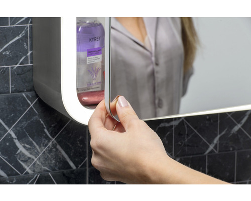 Vrouw opent spiegelkast in de badkamer