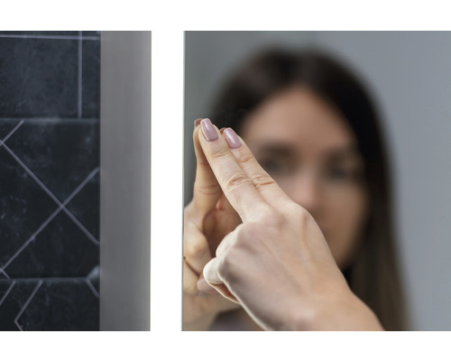 Vrouw raakt een verlichte badkamerspiegel aan