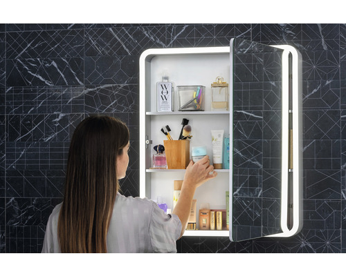 Vrouw voor een spiegelkast met verlichting in de badkamer