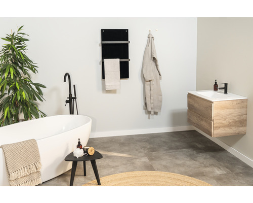 Lichte badkamer met bad, wastafel, handdoekradiator en plant voor een aangename sfeer.