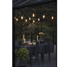 Eettafel met stoelen, kaarsen en verlichting in een kas