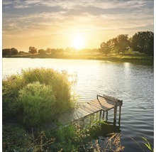 Een steiger leidt naar een meer bij zonsondergang.