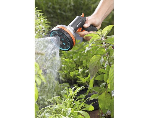 Een hand houdt een Gardena douchekop vast en bewaterd planten.