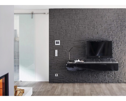 Woonkamer met schuifdeur, grijze stenen muur en zwart tv-meubel