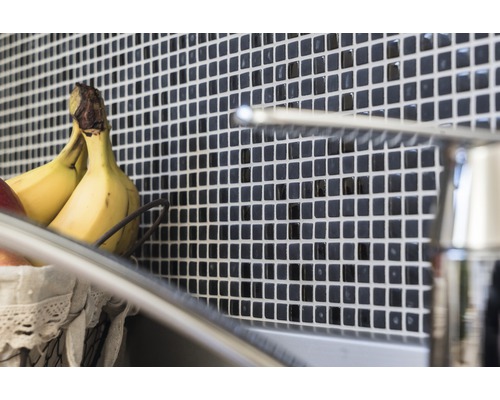 Wandtegels met mozaïekpatroon achter een gootsteen met kraan en fruitmand