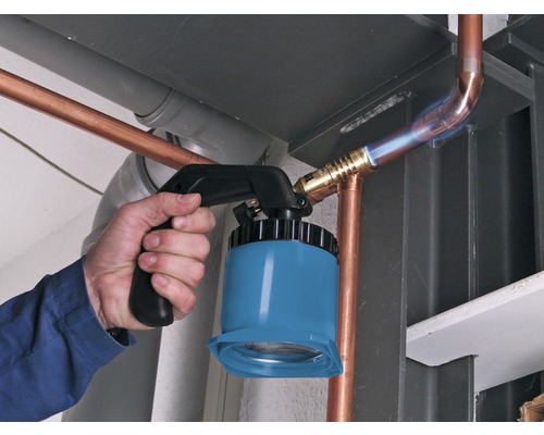 Een vakman soldeert koperen buizen met een soldeerbrander.