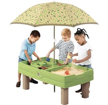 Kinderen spelen aan een groene zand- en watertafel met een parasol