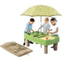 Kinderen spelen aan een zand- en watertafel met parasol.