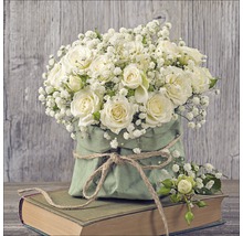 Boeket met witte rozen en gipskruid in een groene papieren zak op een boek