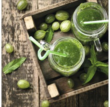 Houten kist met kruisbessen en twee glazen kruisbessensmoothie met rietje