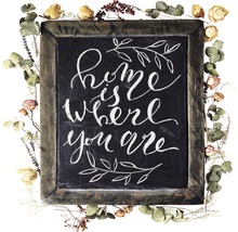 "Decoratief bord met de tekst ""Thuis is waar je bent"", omgeven door gedroogde bloemen"