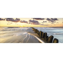 Zonsondergang op het strand met houten palen in het water