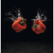 Twee rode paprika''s vallen in het water