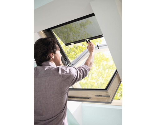 Man bedient een dakraam met insectenbescherming