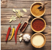 Arrangement van specerijen, knoflook, chilipepers en laurierblaadjes op een houten oppervlak