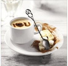 Kop cappuccino met decoratieve lepel, suikerklontjes en chocolade op een bord