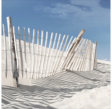 Decoratief houten hek in het zand onder een blauwe hemel