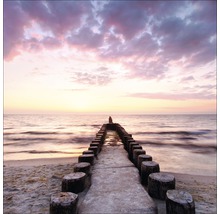 Strand met houten palen in de zee bij zonsondergang