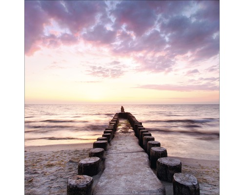 Strand met houten palen in de zee bij zonsondergang