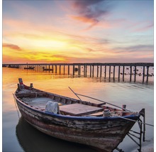 Houten boot aan de kust met een steiger op de achtergrond