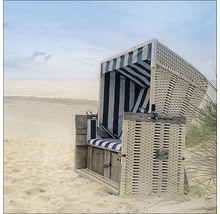 Strandstoel van vlechtwerk met gestreepte kussens op het strand