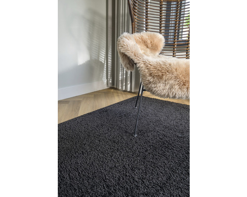 Interieurvoorbeeld met een zwart tapijt, een fauteuil en een schapenvacht