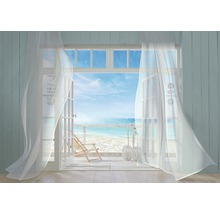 Open deur met uitzicht op strand en zee doorzichtige gordijnen.
