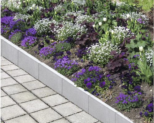 Betonnen gazonrand met bloemen en straatstenen