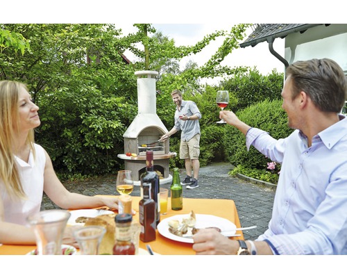Barbecue in de tuin met gemetselde tuingrill en feestende mensen