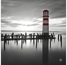 Zwart-witfoto van een vuurtoren aan een meer met houten steiger