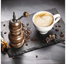 Koffiemolen, kop cappuccino, kandijsuiker en kaneelstokjes op een leisteen bord