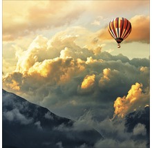 Heteluchtballon boven beboste bergen onder een bewolkte hemel