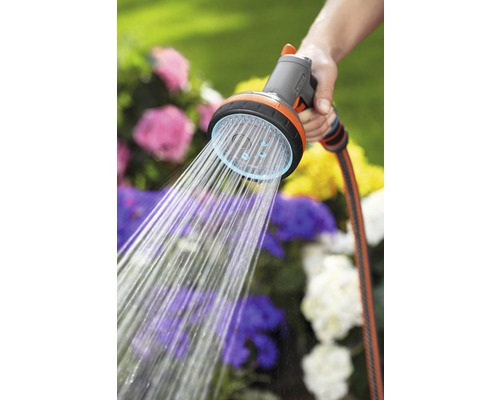 Tuinslangsproeier met waterstraal in de hand voor bloembed