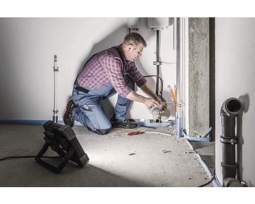 Een installateur werkt aan leidingen in een ruimte.