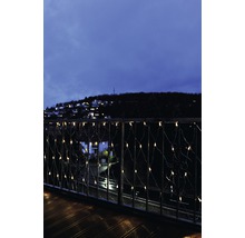 Balkon met lichtjessnoer en uitzicht op een avondlijke stad.
