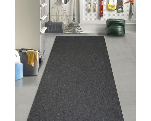 Zwarte rubbermat in een garage met tuingereedschap