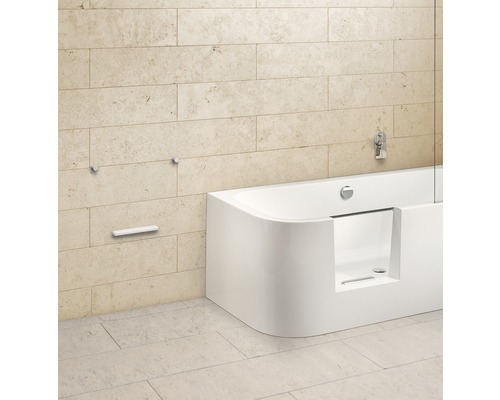 Stijlvolle badkamer met ligbad en armaturen tegen een stenen muur.
