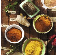 Diverse kruiden zoals paprika, gember en oregano in schalen en als vers ingrediënt op een houten tafel