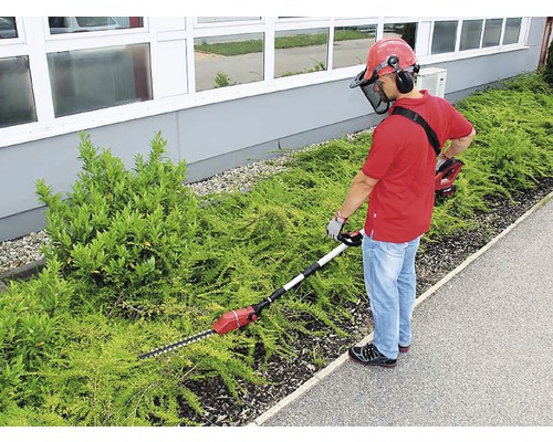 Man snoeit heg met een accu heggenschaar met telescopische steel en veiligheidsuitrusting