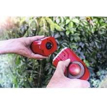 Twee handen houden een elektronische marterverjager vast voor groen loof