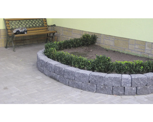 Natuurstenen bloembedomranding met beplanting in de tuin.