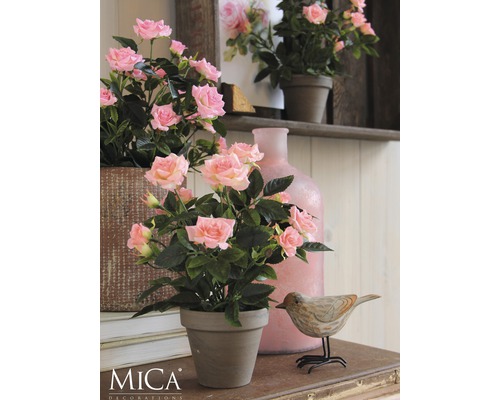 Decoratieve rozen in een pot op een tafel met een houten vogeldecoratie en een vaas.