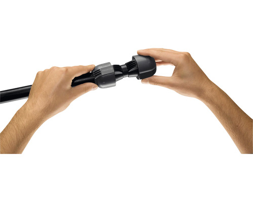 Twee handen monteren een zwart verbindingsstuk op een zwarte buis.