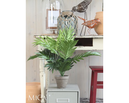 Decoratieve kunstplant in pot op een bijzettafel, omringd door andere decoratieve elementen.